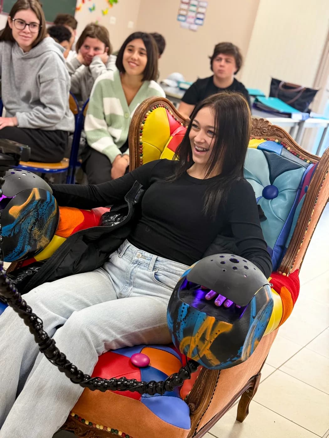 Une élève dans le fauteuil signature AI ANIMO, casques biométriques en main, entourée de camarades